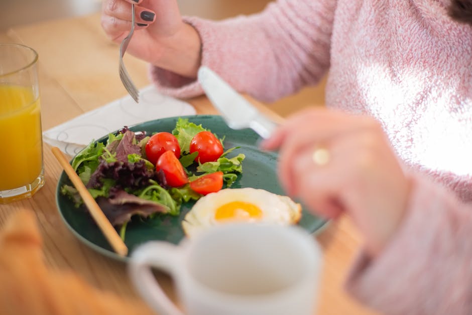 Vrouw aan de keukentafel met een eiwitrijk ontbijt — basis van afvallen met spierbehoud