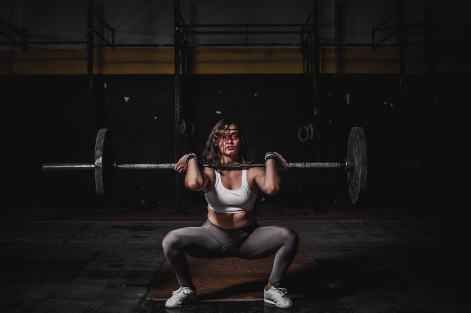 Vrouw met barbell in de sportschool — krachttraining en voldoende eiwit werken als één combinatie