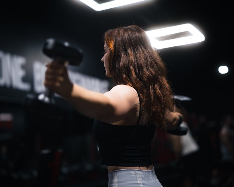 Vrouw met dumbbells doet krachttraining — twee tot drie keer per week is de minimum-prikkel voor spierbehoud